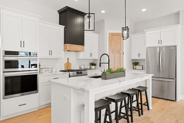 kitchen with white cabinets, stainless steel appliances, and an island with sink