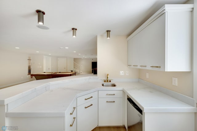 kitchen with stainless steel dishwasher, sink, white cabinetry, and kitchen peninsula