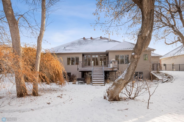 snow covered rear of property with a deck