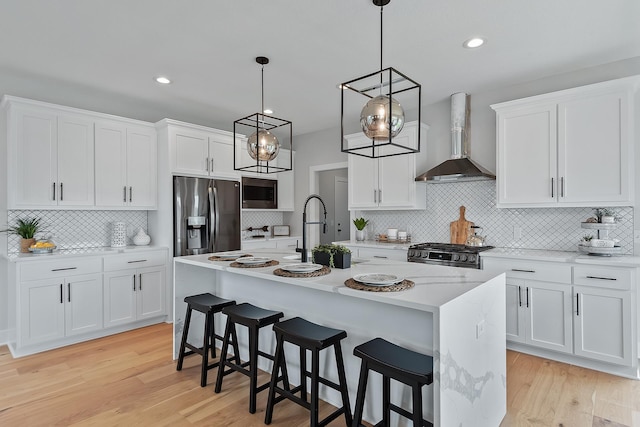 kitchen featuring white cabinets, stainless steel appliances, and wall chimney exhaust hood