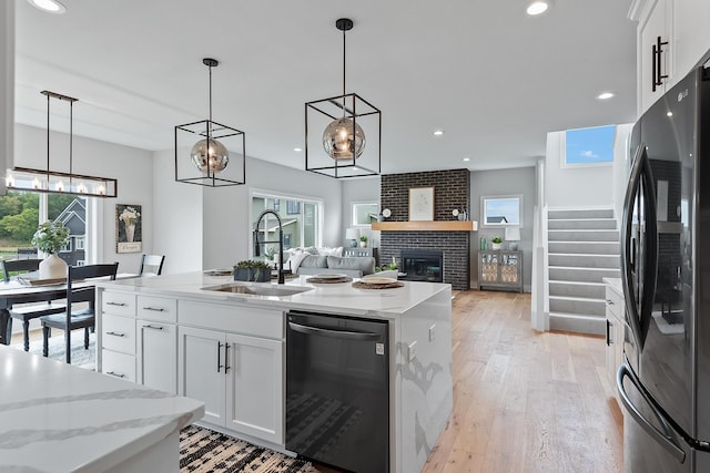 kitchen featuring white cabinets, a fireplace, black dishwasher, and stainless steel refrigerator