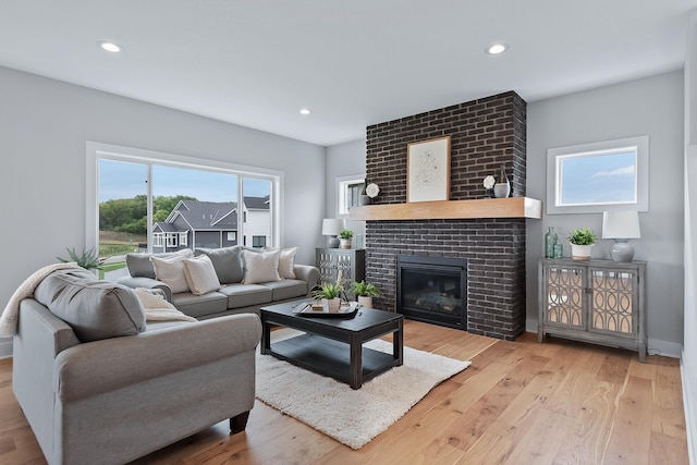 living room with a brick fireplace and light hardwood / wood-style flooring