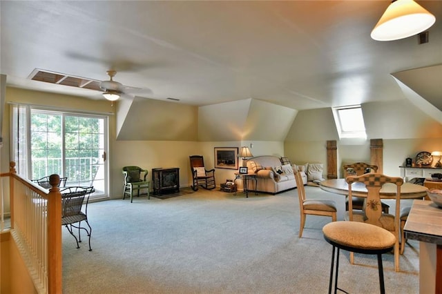 interior space with ceiling fan, a wood stove, and lofted ceiling with skylight