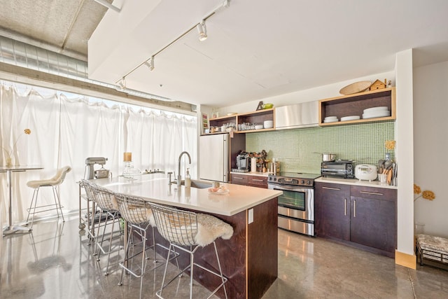 kitchen featuring an island with sink, stainless steel electric range, a breakfast bar area, and sink