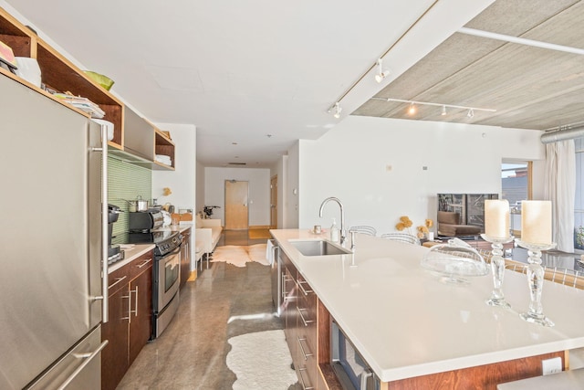 kitchen with sink, a large island, rail lighting, stainless steel appliances, and a kitchen bar