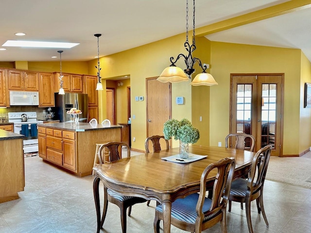 tiled dining space with lofted ceiling and french doors