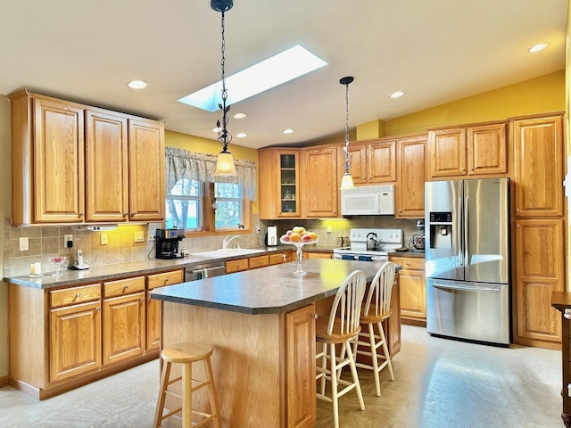 kitchen featuring a kitchen island, a skylight, stainless steel appliances, and backsplash