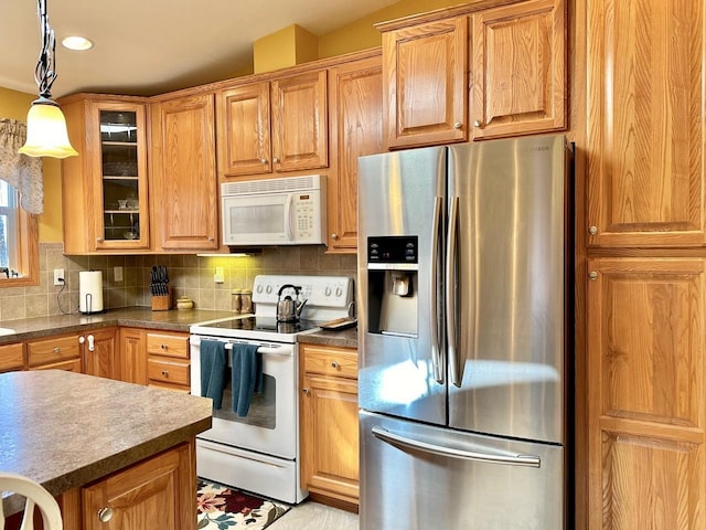 kitchen featuring pendant lighting, decorative backsplash, and white appliances