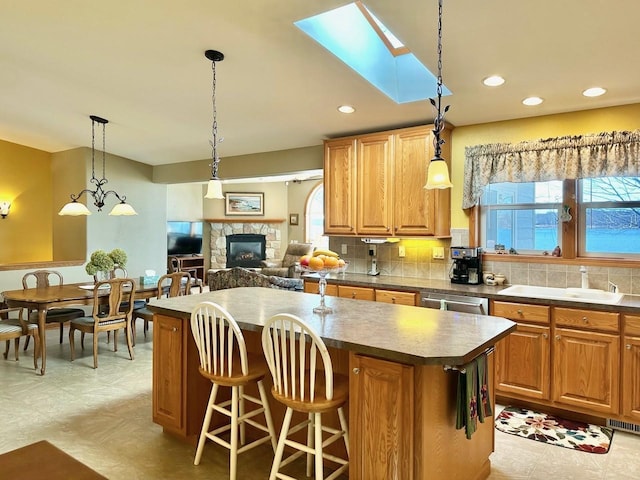 kitchen with sink, light tile patterned flooring, a healthy amount of sunlight, and a stone fireplace