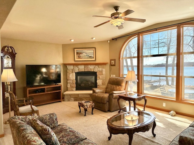 carpeted living room with a fireplace, a water view, and ceiling fan