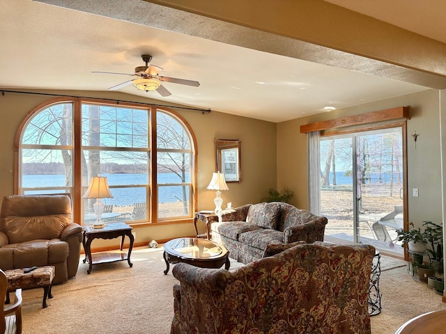 living room featuring light carpet, a water view, a textured ceiling, and ceiling fan