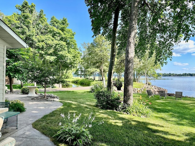 view of home's community with a water view and a lawn