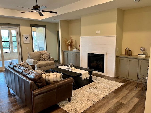 living room featuring ceiling fan, dark hardwood / wood-style floors, and a raised ceiling