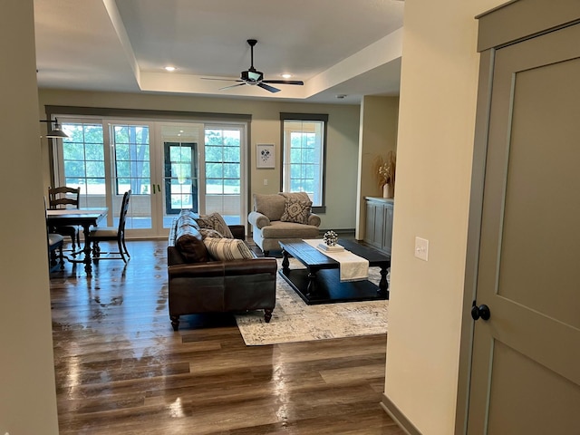 living room with ceiling fan, dark hardwood / wood-style floors, and a raised ceiling