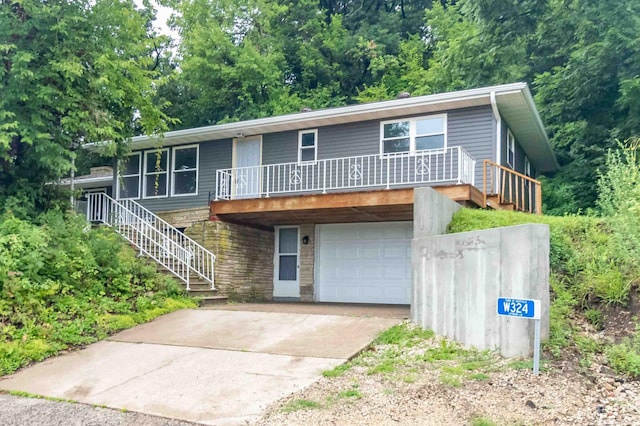 view of front of house with stone siding, stairway, an attached garage, and concrete driveway