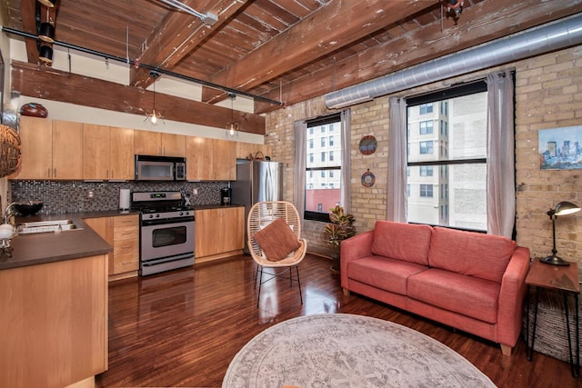 interior space with brick wall, dark hardwood / wood-style floors, sink, and beamed ceiling