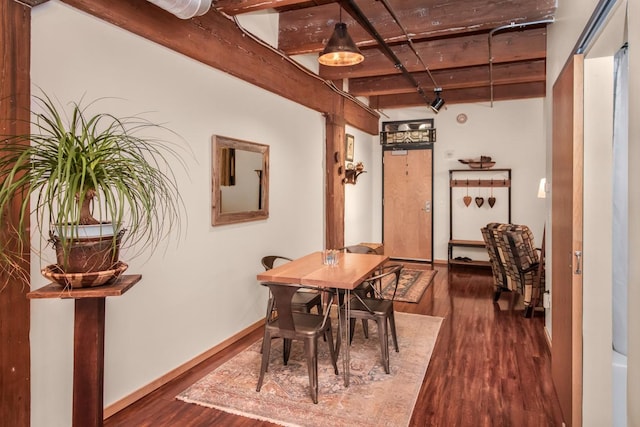 dining area featuring dark wood-type flooring and beamed ceiling