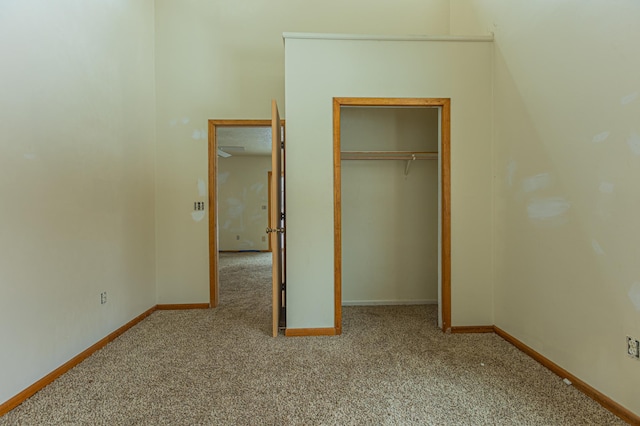 unfurnished bedroom with carpet, a closet, and baseboards