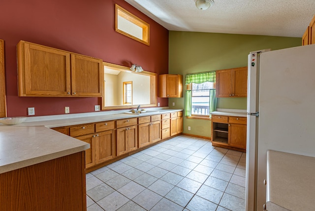 kitchen featuring light tile patterned floors, freestanding refrigerator, vaulted ceiling, a textured ceiling, and light countertops