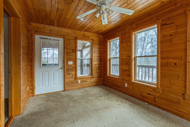 interior space with a ceiling fan, wood ceiling, and wooden walls