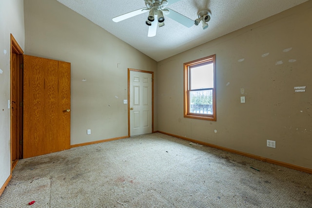 unfurnished room with baseboards, ceiling fan, vaulted ceiling, a textured ceiling, and carpet flooring