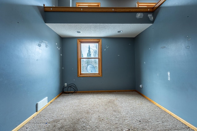 carpeted empty room featuring a textured ceiling, visible vents, and baseboards