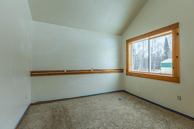 carpeted empty room featuring lofted ceiling, a textured ceiling, and baseboards