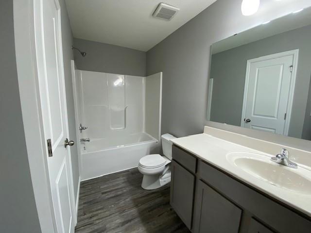 full bathroom with shower / bathtub combination, vanity, toilet, and hardwood / wood-style flooring