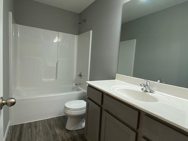 full bathroom featuring toilet, washtub / shower combination, oversized vanity, and hardwood / wood-style flooring