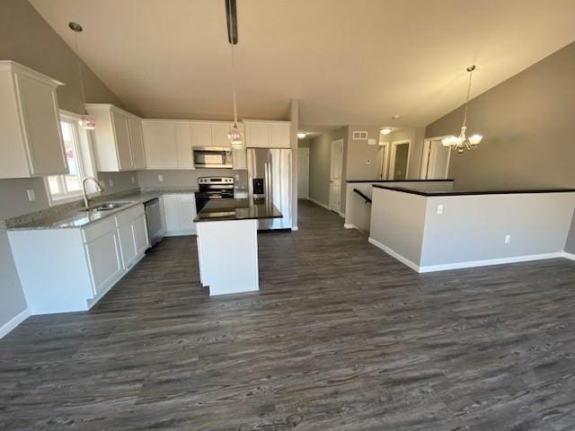 kitchen with dark hardwood / wood-style floors, pendant lighting, stainless steel appliances, an inviting chandelier, and a center island