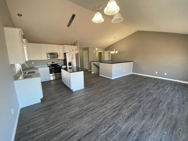 kitchen featuring appliances with stainless steel finishes, an inviting chandelier, a kitchen island, vaulted ceiling, and decorative light fixtures