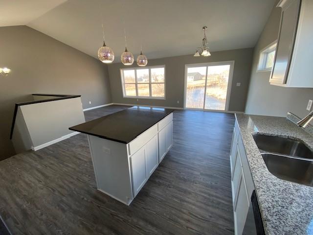 kitchen with a kitchen island, a notable chandelier, white cabinetry, hanging light fixtures, and dark hardwood / wood-style floors