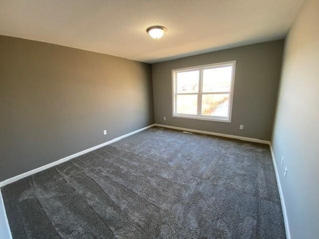 spare room with dark carpet