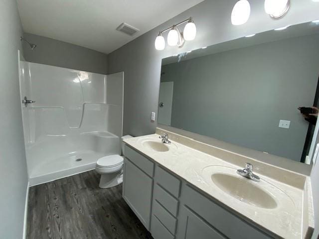 bathroom with a shower, toilet, double vanity, and hardwood / wood-style flooring