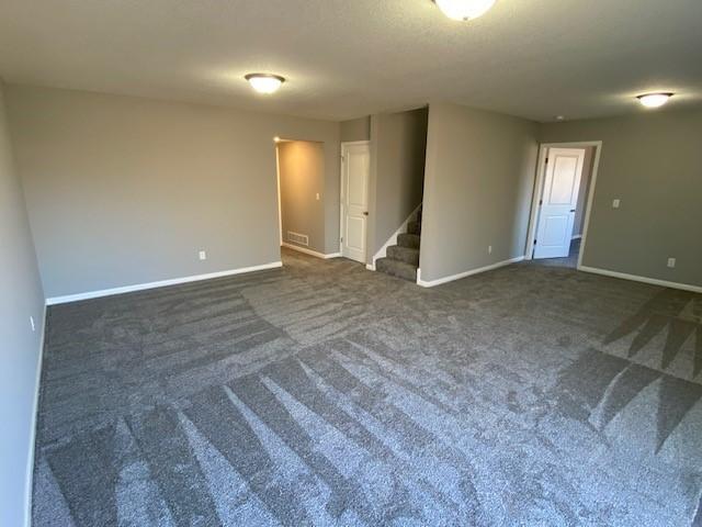 spare room featuring dark colored carpet