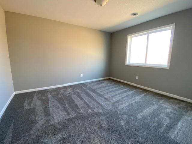 unfurnished room with dark carpet