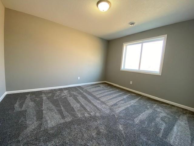 unfurnished room featuring dark carpet