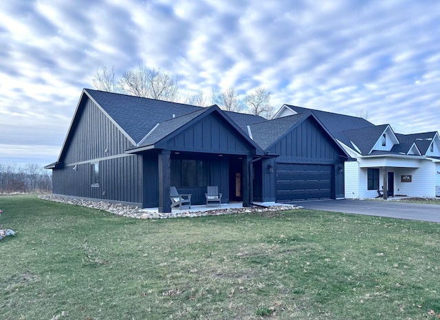 view of front of property featuring a patio area, a front yard, and a garage