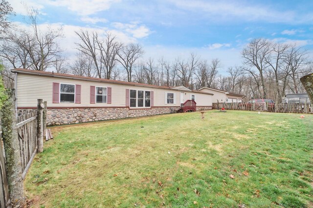 exterior space with stone siding, a lawn, a fenced backyard, and a wooden deck