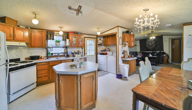 kitchen with lofted ceiling, a sink, white range with gas cooktop, range hood, and washing machine and clothes dryer