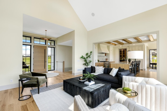 living room featuring light wood-type flooring, sink, beamed ceiling, and high vaulted ceiling