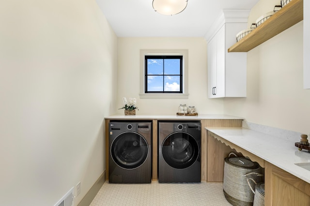 washroom featuring separate washer and dryer and cabinets