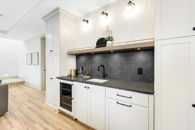 kitchen with white cabinets, backsplash, beverage cooler, light hardwood / wood-style flooring, and sink