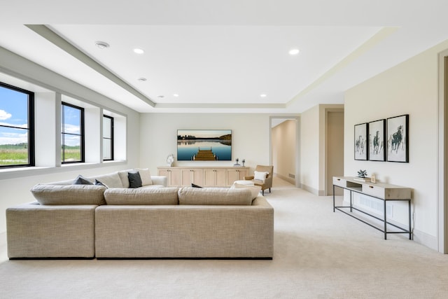 living room with a tray ceiling and light colored carpet