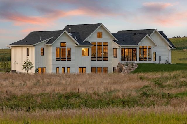 back house at dusk with a sunroom