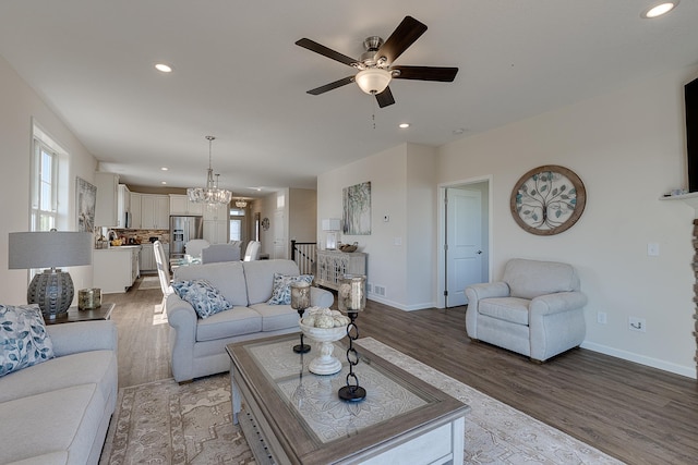 living room with ceiling fan with notable chandelier and hardwood / wood-style flooring