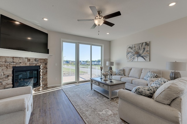 living room featuring ceiling fan, hardwood / wood-style flooring, and a fireplace