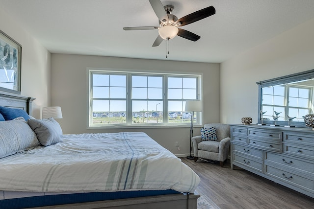 bedroom with ceiling fan, hardwood / wood-style floors, and multiple windows