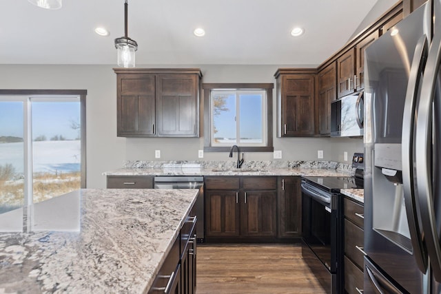 kitchen with sink, wood-type flooring, dark brown cabinets, pendant lighting, and stainless steel appliances