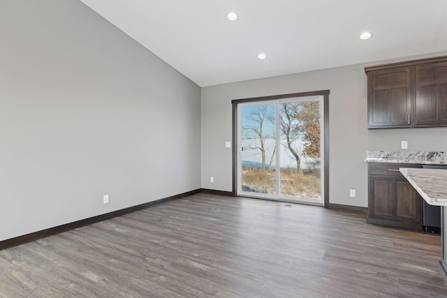 unfurnished dining area featuring dark wood-type flooring and lofted ceiling